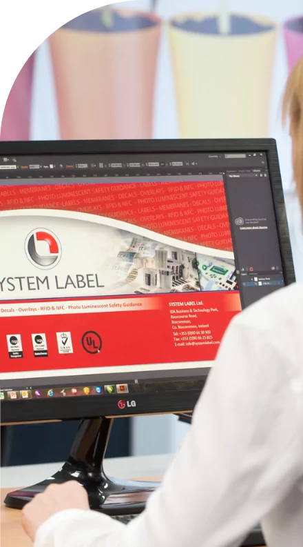 A woman is looking at a computer screen with a system label on it, featuring custom labels.