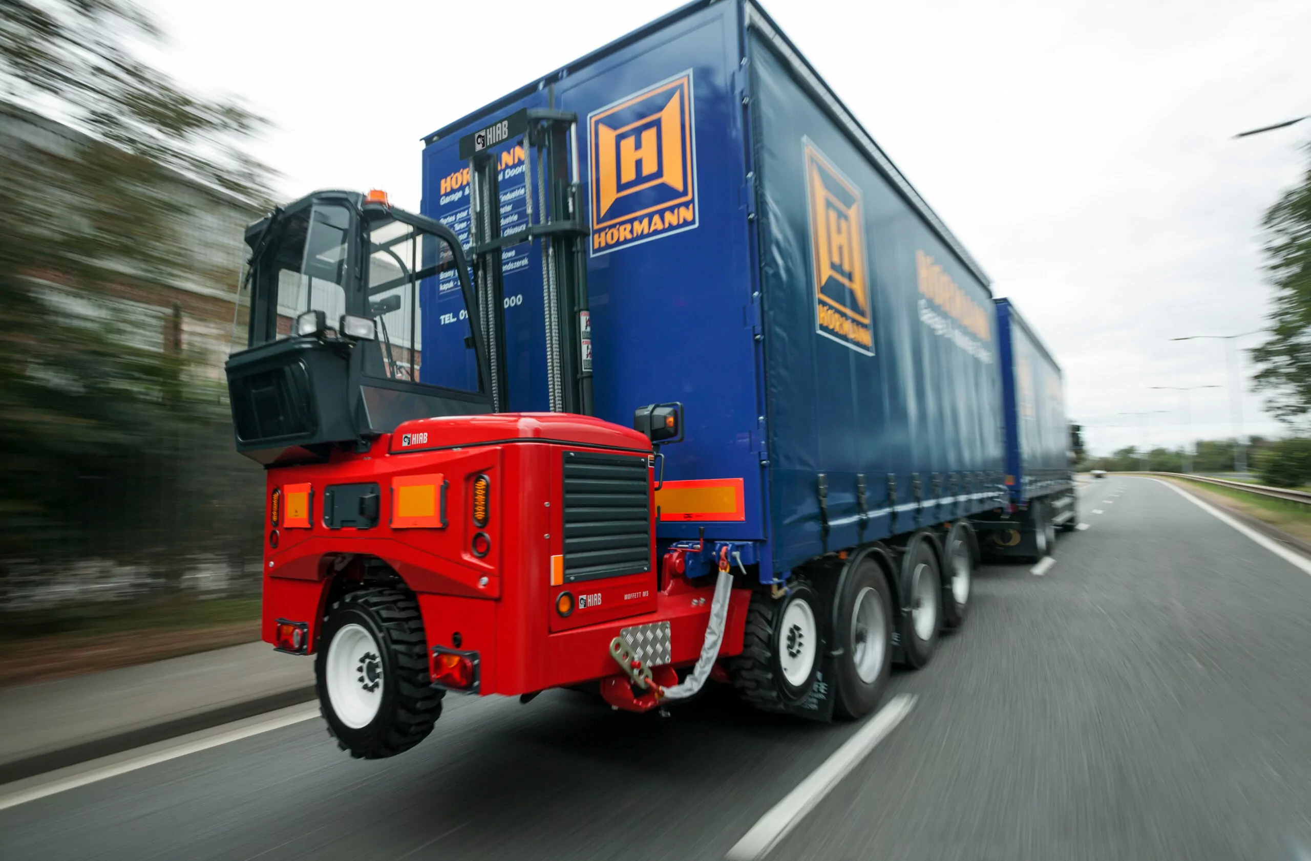 A blue truck with high quality labels driving down the road.